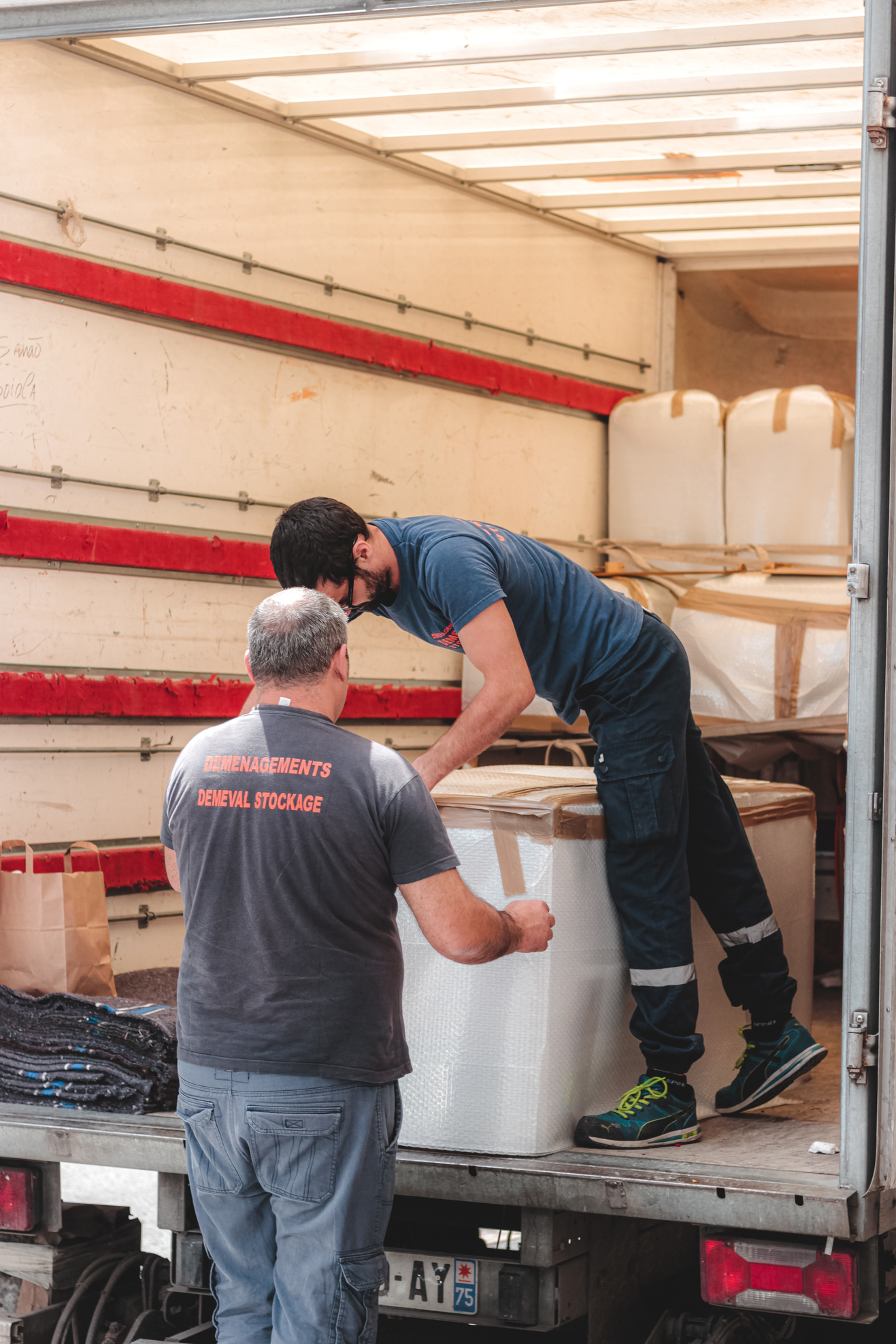 Removal porters unloading truck with big boxes